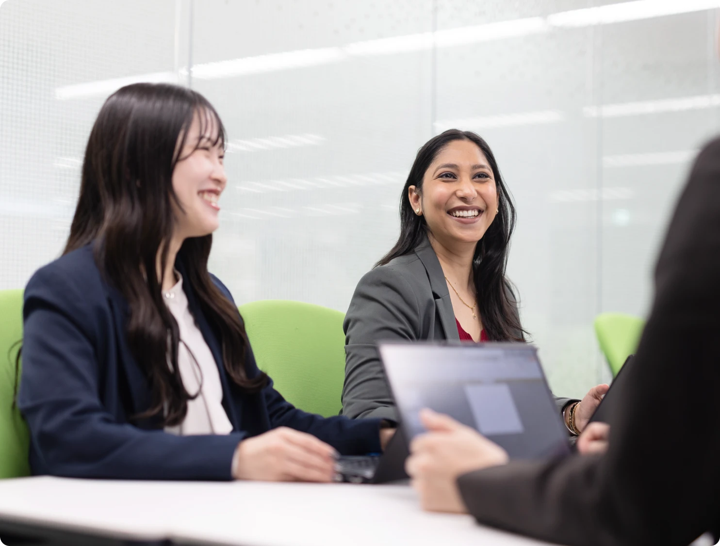 オフィスでノートPCを囲みながら笑顔で打ち合わせをするビジネスパーソン