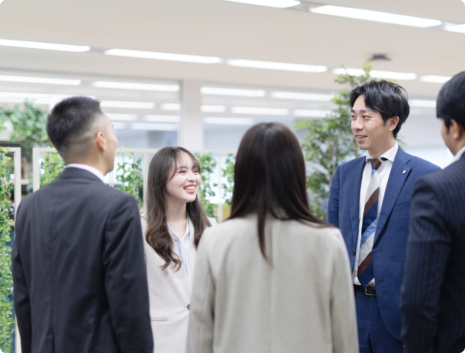 オフィスで複数の社員が談笑しながらコミュニケーションを取る様子